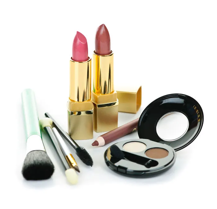 Makeup products including lipsticks, brushes, and eye palette arranged artistically.