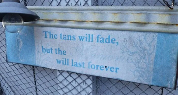 Sign design fail with faded words, showing unreadable message on a weathered metal background.