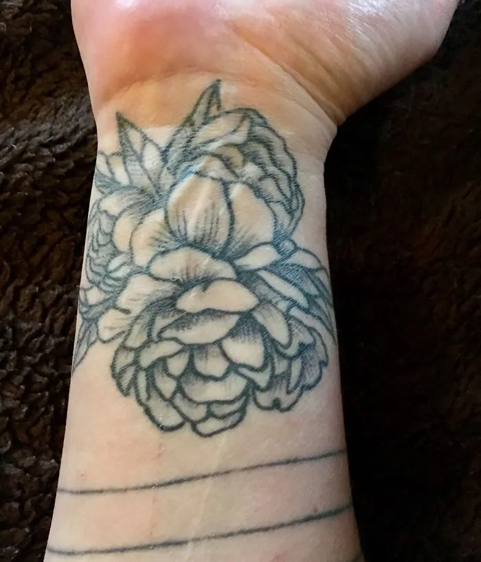 Floral tattoo covering a wrist scar, turning it into art.