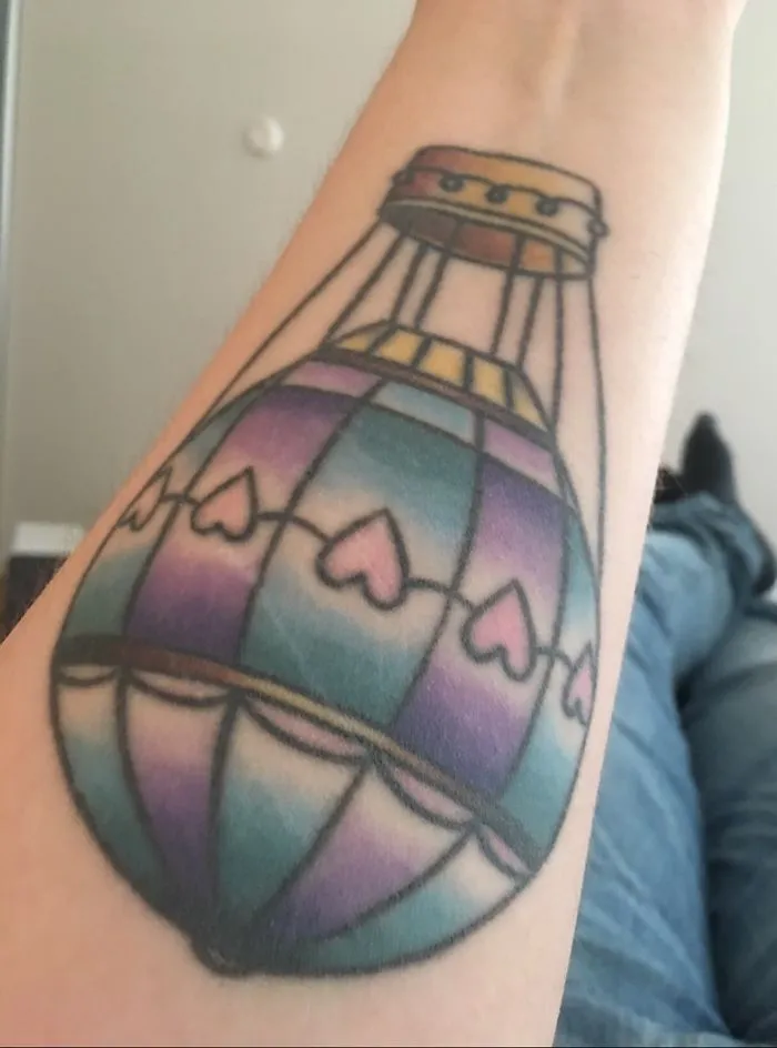 Colorful hot air balloon tattoo transforming a scar into art on an arm.