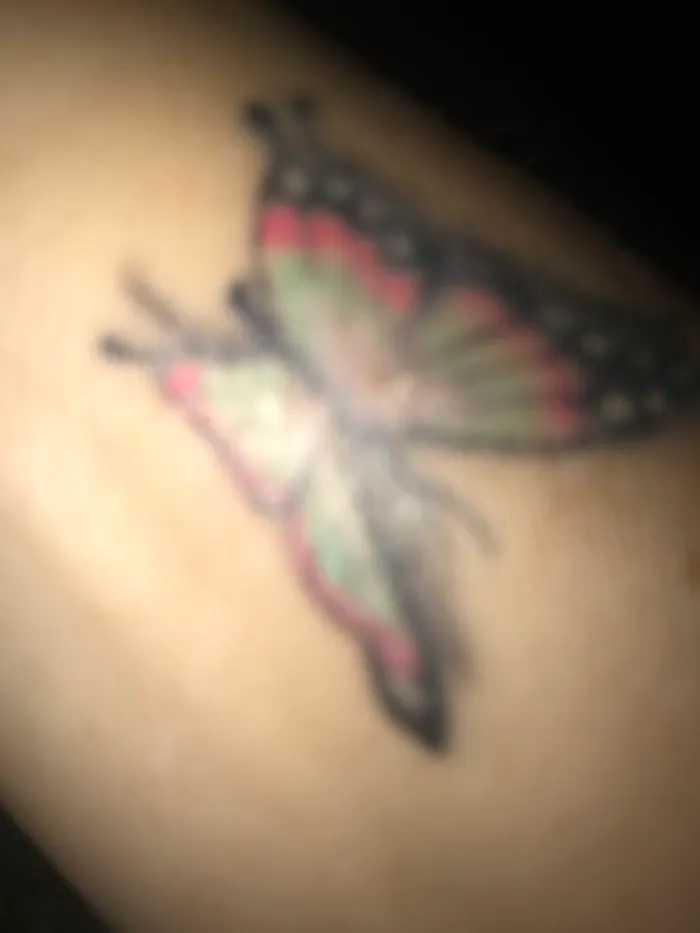 Butterfly tattoo transforming a scar into art on skin.