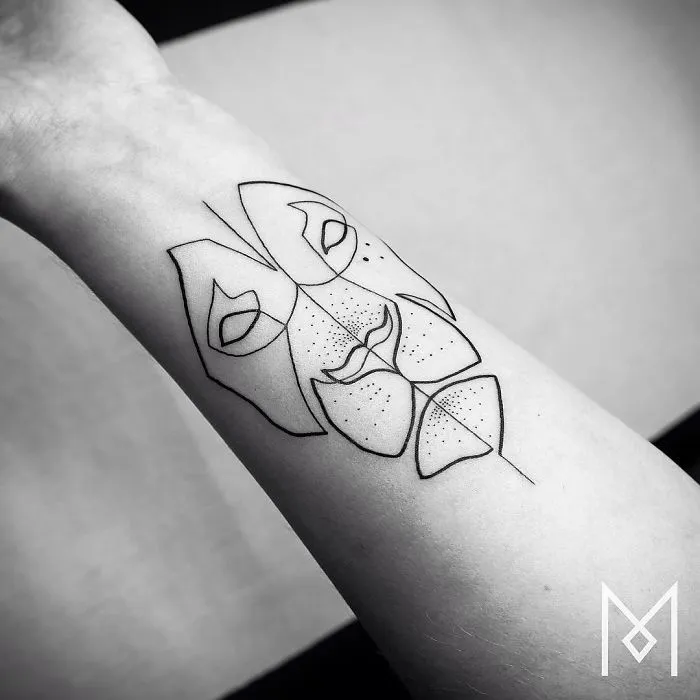 Single continuous line tattoo by Mo Ganji depicting a geometric face on a forearm.