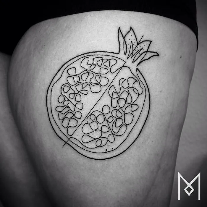 Single-line pomegranate tattoo by Mo Ganji on skin, showcasing intricate continuous design.