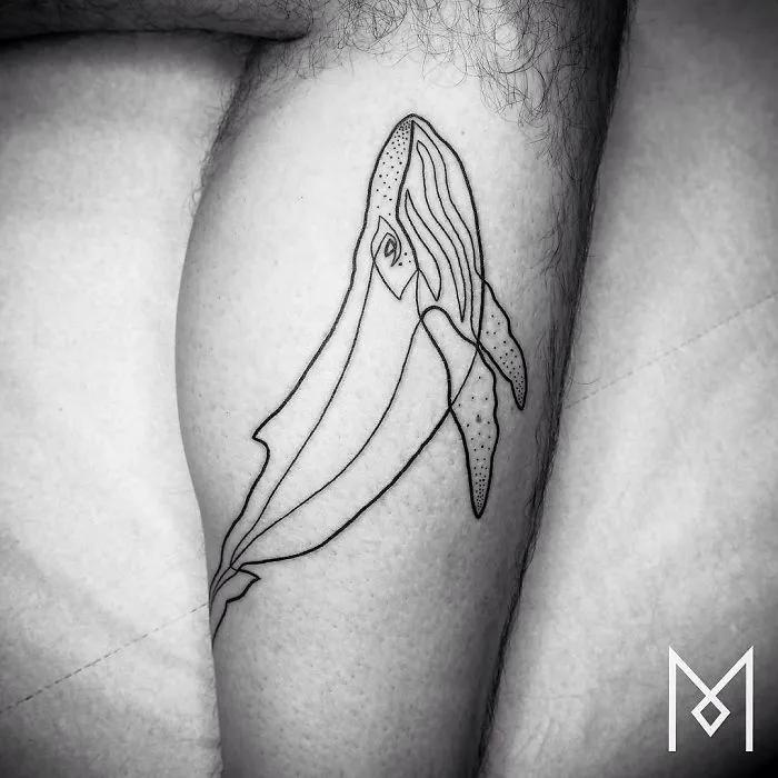 Single continuous line whale tattoo by Mo Ganji on a person's leg, showcasing minimalist artistry.