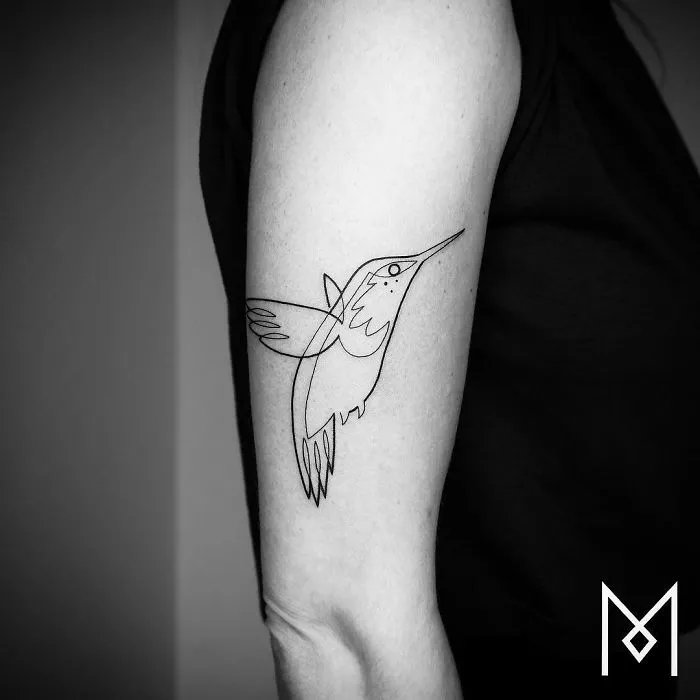 Single line tattoo of a hummingbird on an arm by Mo Ganji.