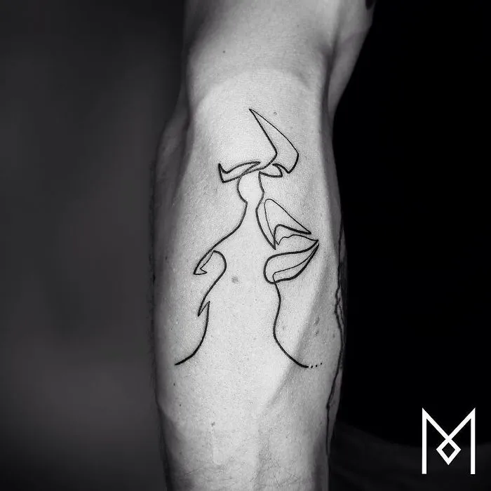 A single continuous line tattoo by Mo Ganji, depicting two faces on an arm.