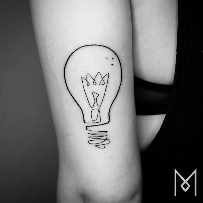 Single line tattoo of a light bulb on an arm, designed by Mo Ganji.