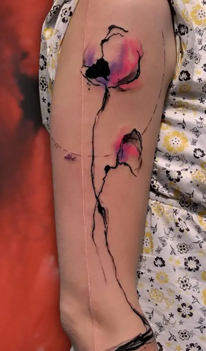 Tattoo art creatively transforms a scar into a floral design on an arm.