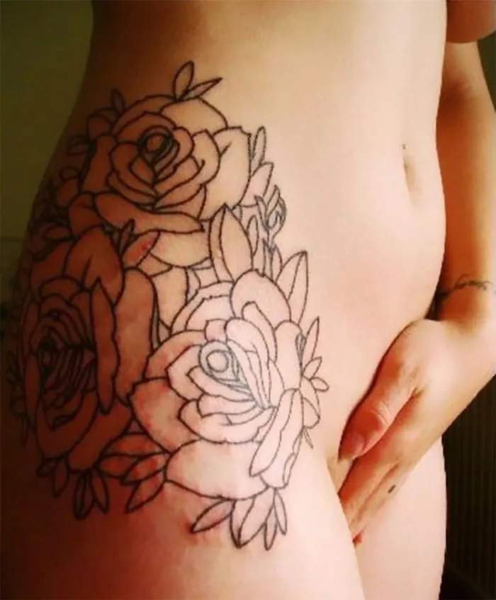 Floral tattoo covering a scar on the hip, transforming it into art.