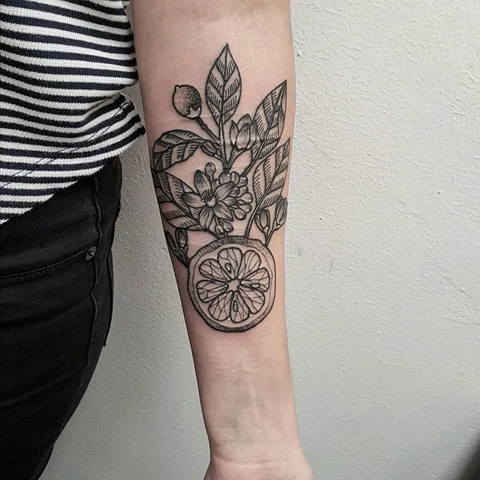 Floral and citrus tattoo design covering a forearm scar, turning it into a work of art.
