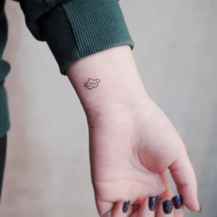 Minimalist wrist tattoo of a small heart on a person's arm, showcasing tiny discreet body art.