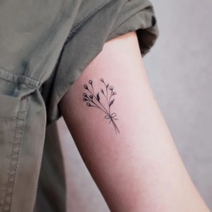 Minimalist tattoo of a delicate bouquet on an arm, highlighting love for subtle ink designs.
