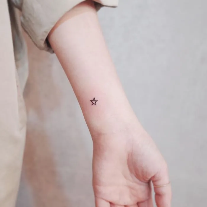 Minimalist tiny star tattoo on a wrist, showcasing discreet design for tattoo enthusiasts.