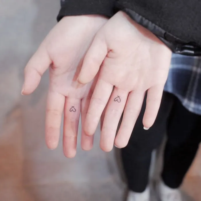 Minimalism tattoos on fingers, featuring tiny heart designs for a subtle, discreet look.