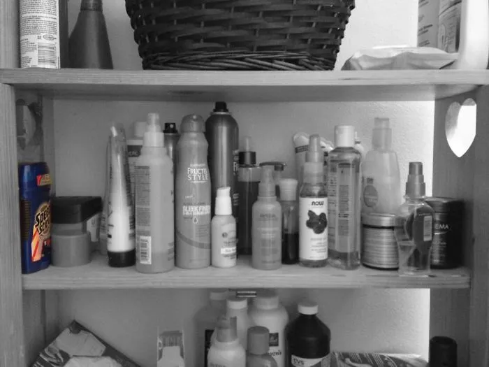 Bathroom shelf cluttered with various toiletries and personal care products, humorously illustrating a married couple's life.