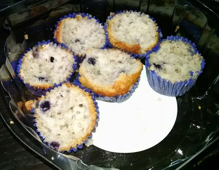 Blueberry muffins in a plastic container, showcasing the humor in married life through shared treats.