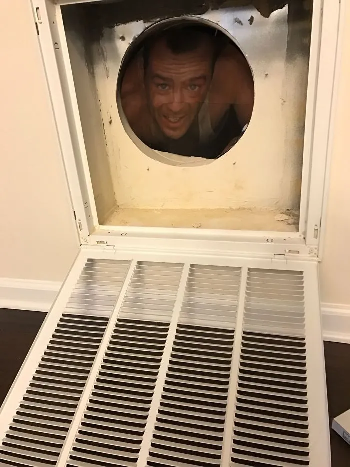 Man in a vent peeking with a playful smile; humorous moment highlighting funny married life.