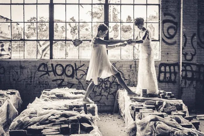Two woman in dresses walking in abandoned building 