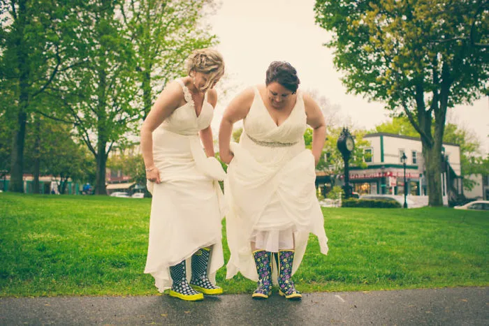 two women with wedding dresses with rubber boots 