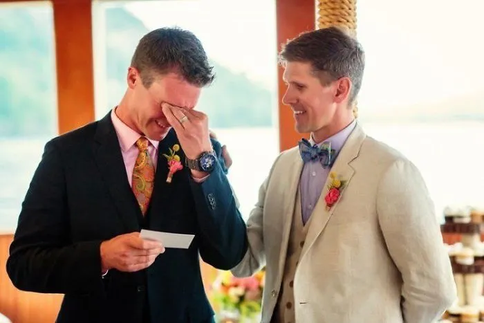 Two man standing and one of the is crying and holding a paper 