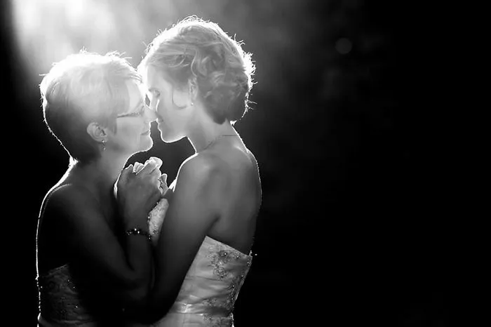 two woman holding hands and kissing each other 