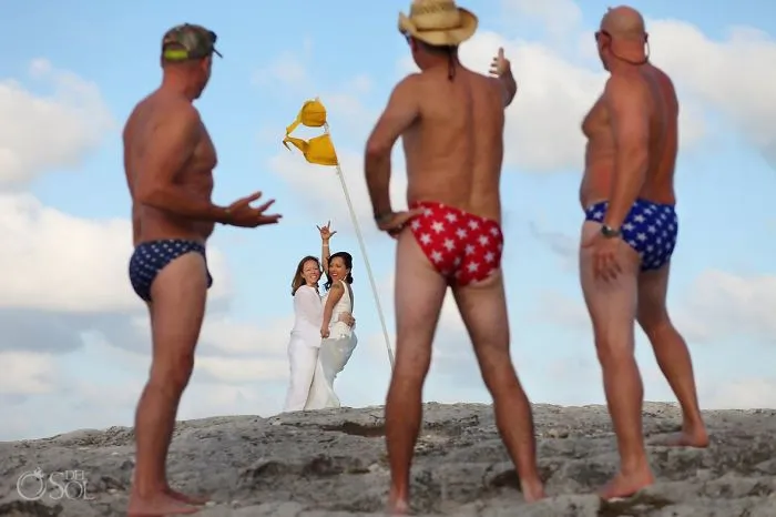 Three men in underwear looking at two happy woman hugging 