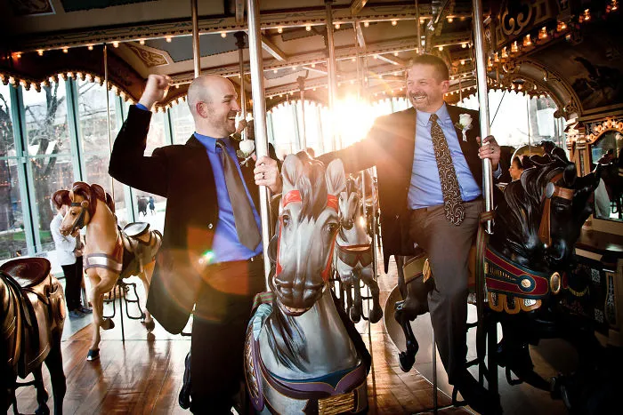 Two happy men riding on carousel 
