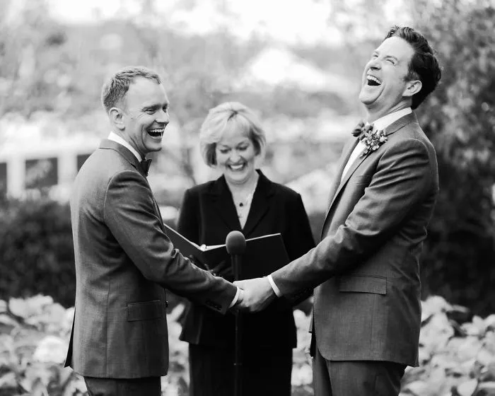 Two men holding hands near a pastor 