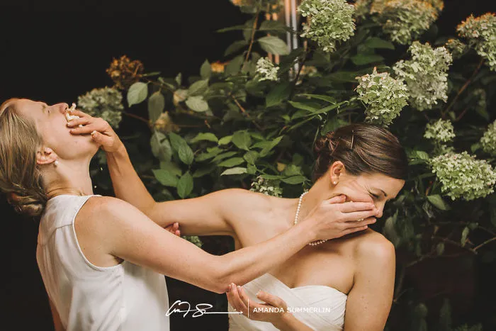 Two woman feeding each other wedding cake 