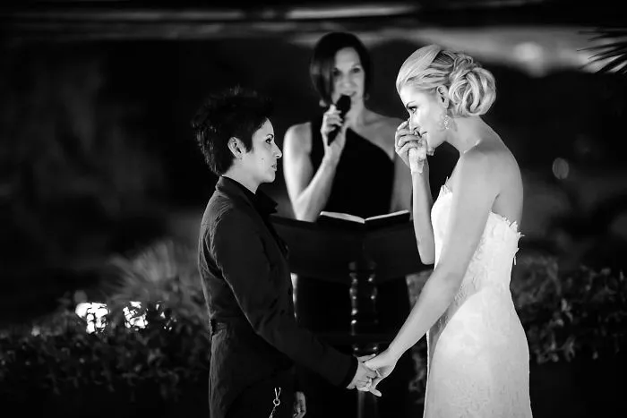 Two woman looking at each other and crying near a pastor 