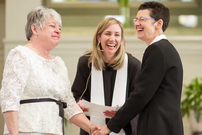 Two happy woman standing near a pastor 