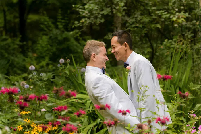 Two happy men looking at each other while being surrounded by flowers 