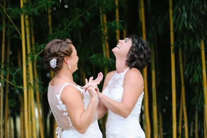 Two happy women holding hands and looking up 