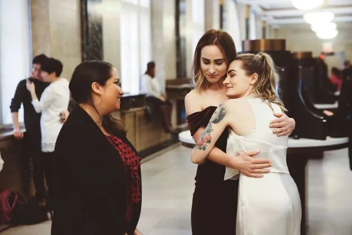 Two happy women hugging near a pastor 