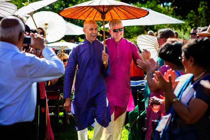 Two happy men walking with an umbrella 