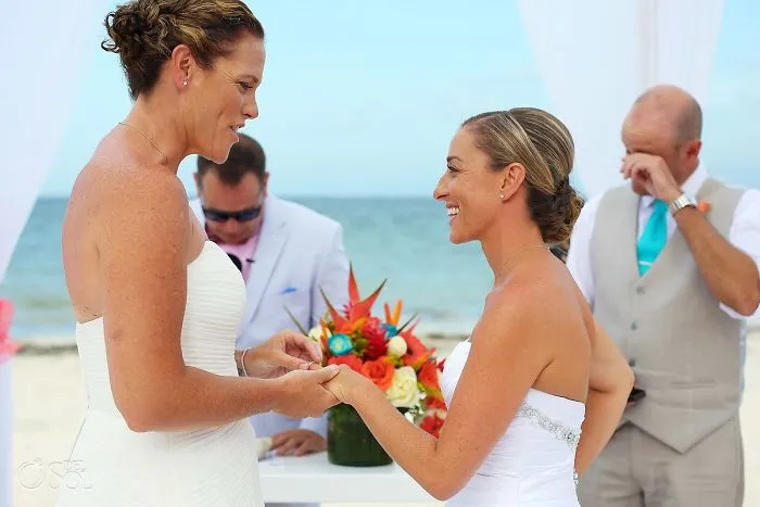 Two women looking at each other and holding hands 