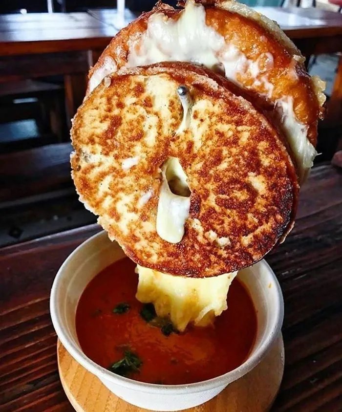 Queso tostado en un gancho suspendido sobre un cuenco de sopa