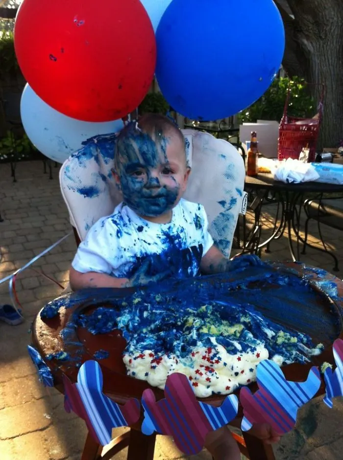 Child covered in blue icing with balloons behind, humorously illustrating what happens when you leave kids alone.