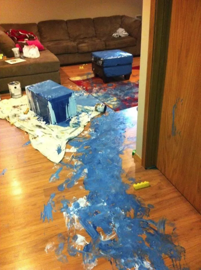 Blue paint spill on the floor showing a mess in the living room after leaving kids unsupervised.