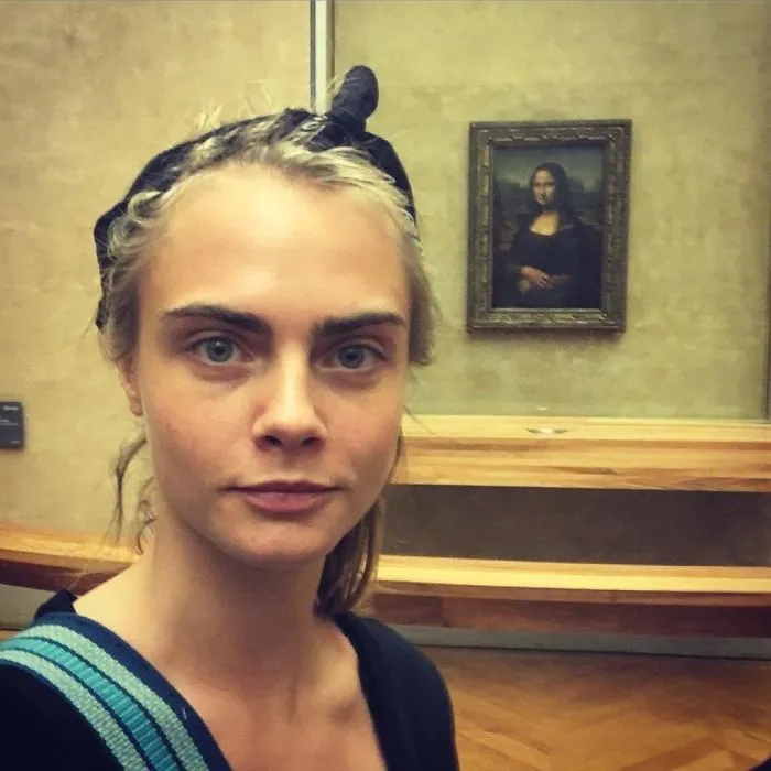 Person without makeup taking a selfie in front of the Mona Lisa painting.