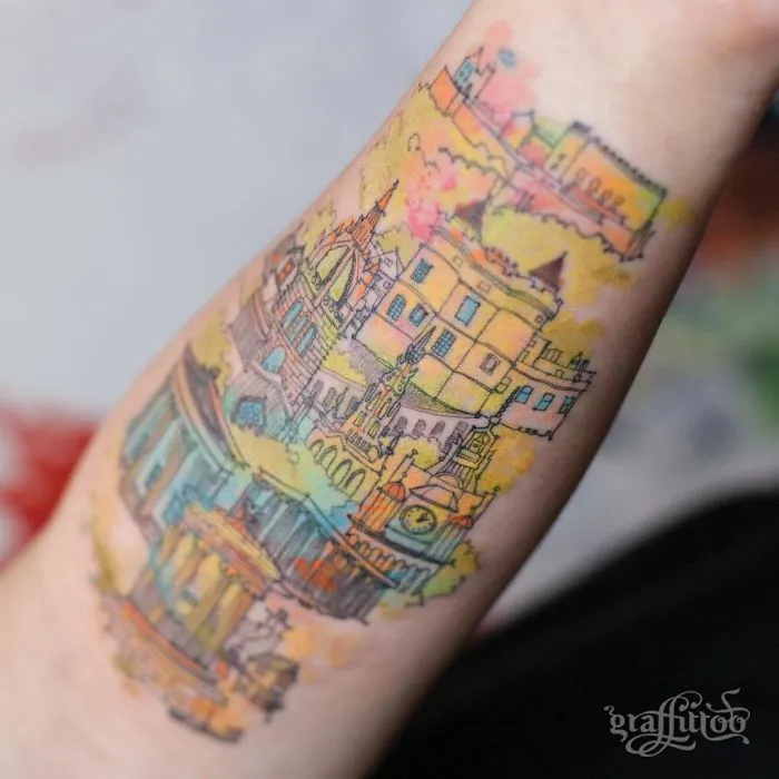 Colorful architecture tattoo on forearm with detailed buildings and vibrant watercolor effects.