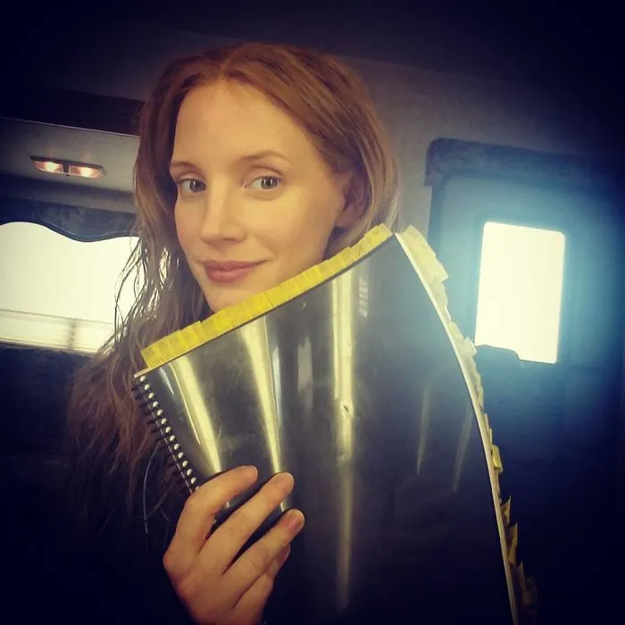 Person holding a notebook, showcasing a natural look without makeup.