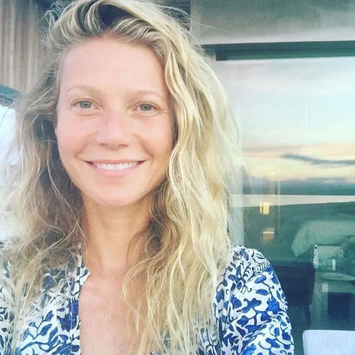 A celebrity smiling without makeup, showcasing natural beauty.