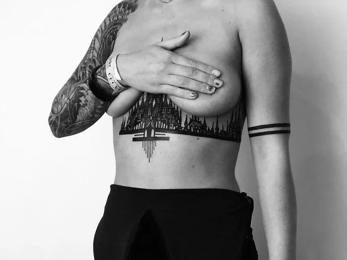 A person with an intricate architecture tattoo across the chest, showcasing detailed cityscape design.