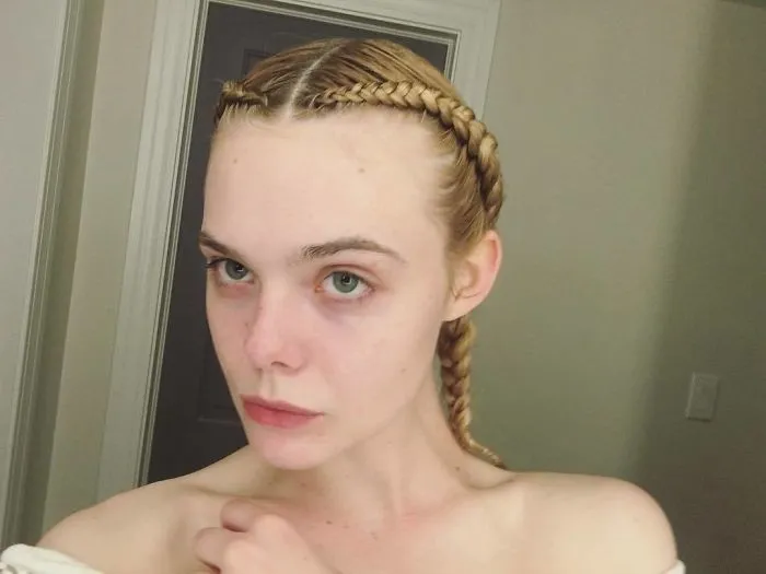 Celebrity without makeup, with braided hair, showing natural skin in a candid setting.