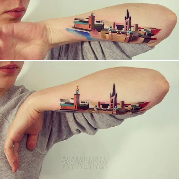 Colorful architecture tattoo on forearm, featuring striking geometric shapes and vibrant cityscape design.
