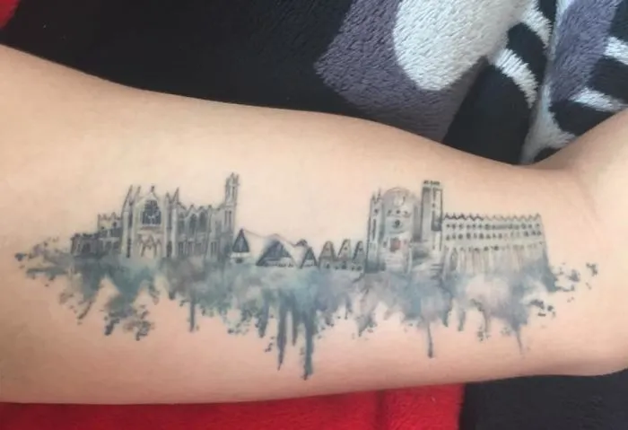 Architectural tattoo on forearm featuring city skyline and famous landmarks.