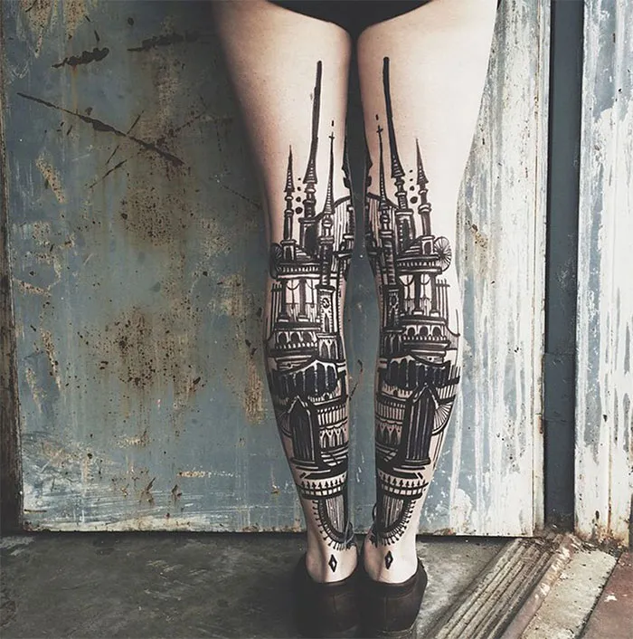 Architecture tattoo of intricate building design inked on legs, set against a rustic background.