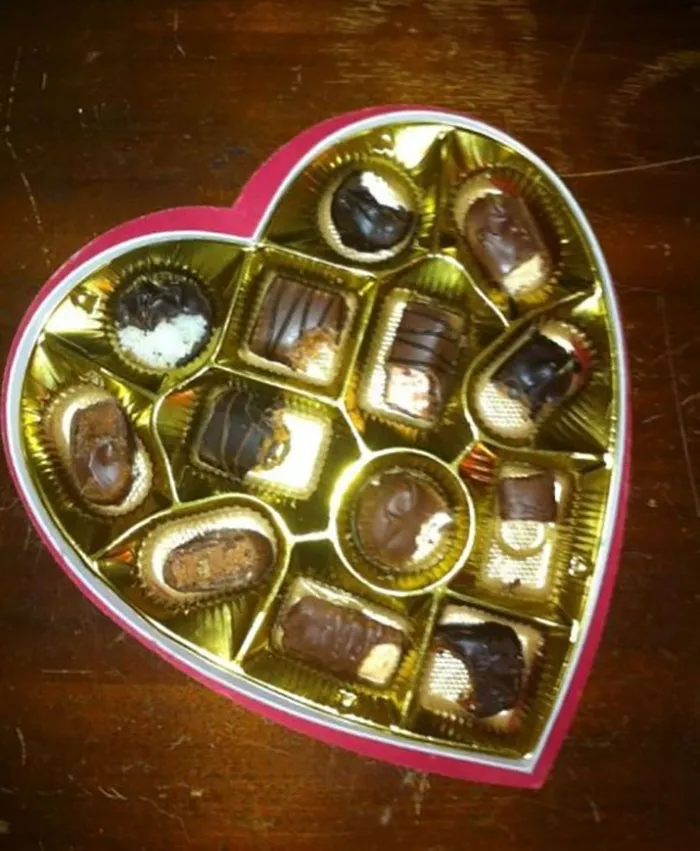 Heart-shaped chocolate box filled with nibbled pieces, showing the fun chaos when kids are left alone.
