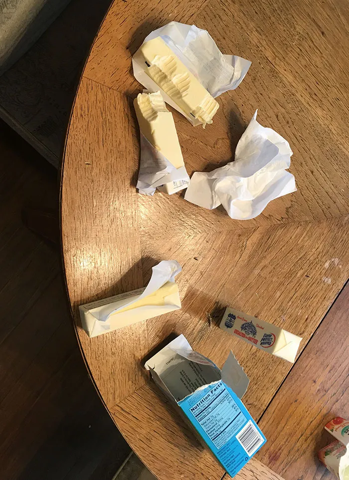 Butter sticks with bite marks on a wooden table, showing a humorous moment when kids are left alone.